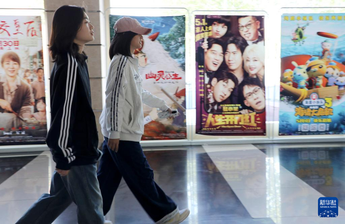 5月3日，在山东省滨州市博兴县一家影城，观众从电影海报前经过。