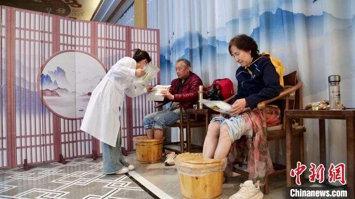 “五一”假期，宕昌县康养驿站内，工作人员为体验中药足浴的游客介绍当地中药茶饮。　中新社记者 闫姣 摄