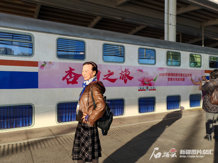 　　3月27日，在乌鲁木齐站，“银发专列”旅客在列车前合影留念。石榴云/新疆日报记者 逯风暴摄