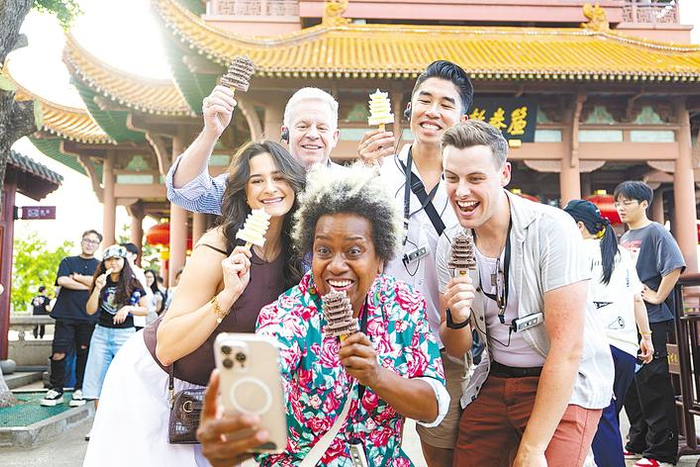 5月5日，《日落大道》团队成员畅游武汉，在黄鹤楼前手持黄鹤楼雪糕打卡拍照。（湖北日报全媒记者 何宇欣 实习生 李昕蓉 摄）