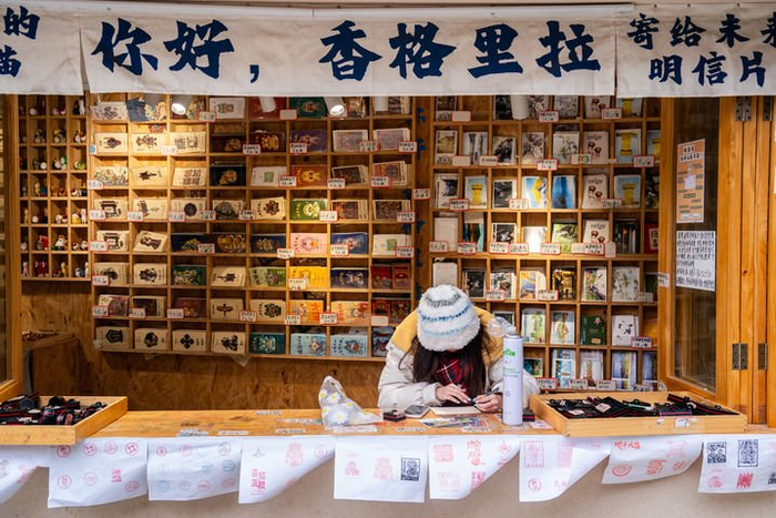 一名游客在云南省迪庆州香格里拉市独克宗古城写明信片（2025年3月7日摄）。新华社记者 胡超 摄