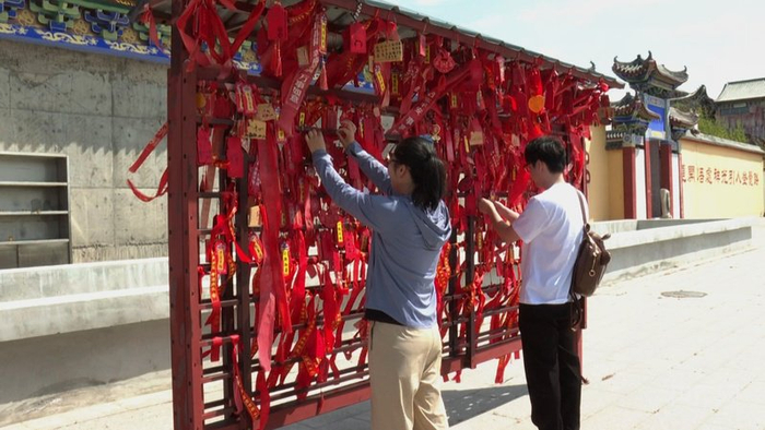 游客正在千佛洞许愿墙上挂许愿牌  （央广网发  罗佳妮  摄）
