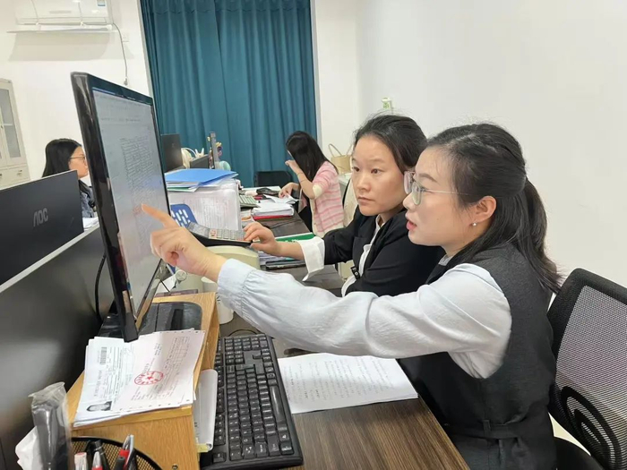 任锦（左一）帮助企业申报信息