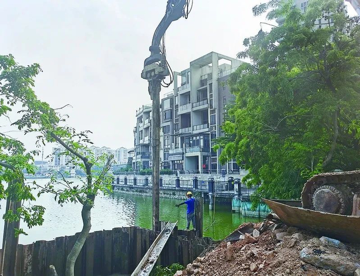 △在端州区彩云路，项目施工人员将钢板插入湖中形成围堰，方便修建排水口。肇庆市融媒体中心记者 潘粤华 摄