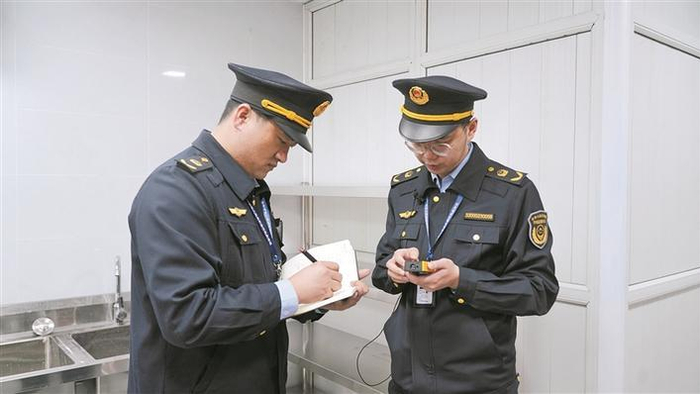 　　二师铁门关市市场监管局综合行政执法支队的工作人员为商户测量门店面积（摄于4月16日）。 魏怀娟 摄