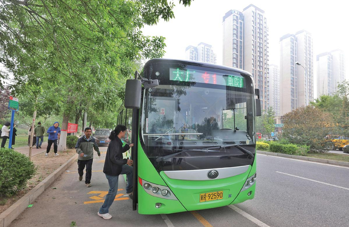 5月8日，河北大厂潮白河孔雀城榕枫园小区西门前公交站，乘客排队乘车。 摄影/新京报记者 王贵彬