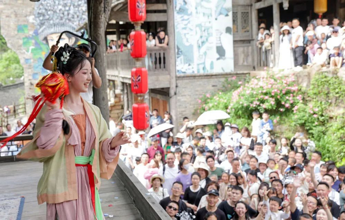 5月1日，在贵州省遵义市乌江寨景区，身着传统服饰的年轻人与游客进行抛绣球互动。新华社发（袁福洪摄）