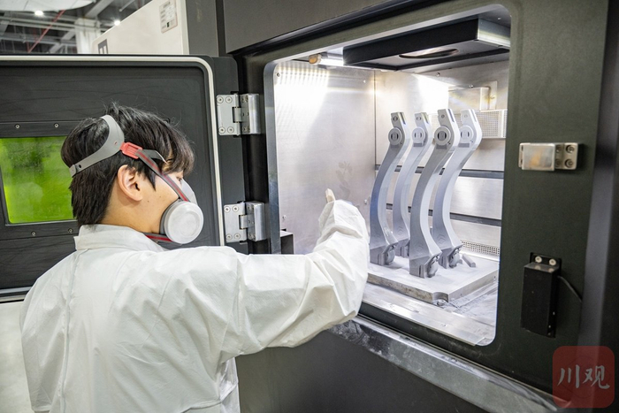 四川五八增材科技有限公司内，工作人员操作“金属3D打印机”，正在“打印”机器狗的下肢。摄影/赵明