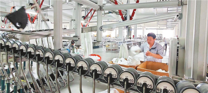 辽宁鸿邦装备技术有限公司生产车间里，滤袋沿着自动轨道有序轮转，工人坚守岗位熟练操作。