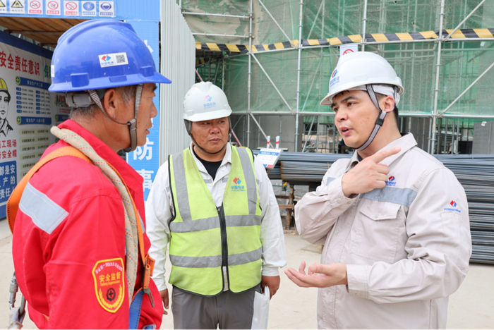 丁建（右）与同事进行工作交流