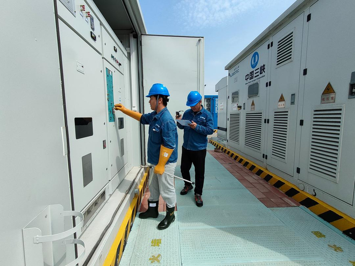 范博与同事巡检、查看储能电柜运行情况。 