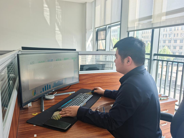 工业互联网运维员孙奇才在看企业报表，分析企业运营管理数据。