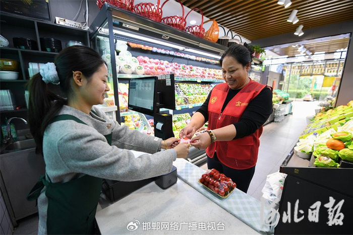5月8日，邯郸市复兴区将相苑社区志愿者（右）通过志愿者服务卡购买水果。董源摄