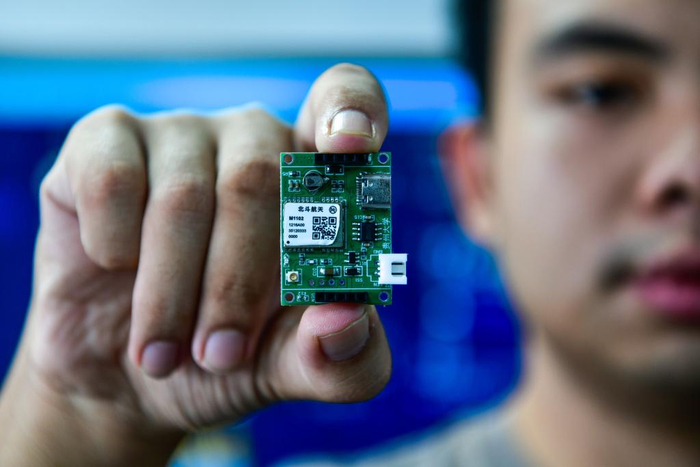 资料图：一名学生展示一款高精度北斗定位芯片。（图源：新华社）