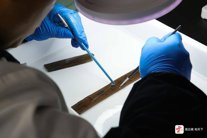 工作人员用毛刷仔细清理出土的简牍。