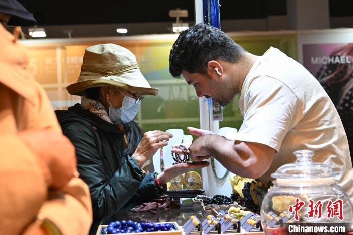 图为拉萨进口商品展览会现场，土耳其商人(右)向顾客介绍、推销自己的商品。中新社记者 贡嘎来松 摄
