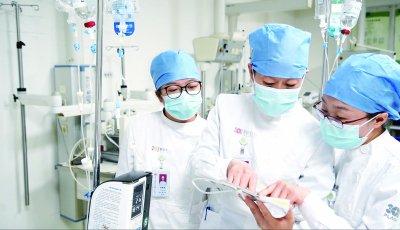 秦玉玲(中)与护理人员讨论患者病情和护理方案。郭阳虎/摄