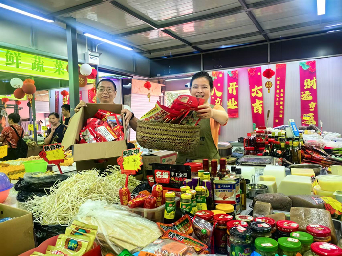 相邻摊位的闵老板和付老板展示5月17日上午收到的消费券直补