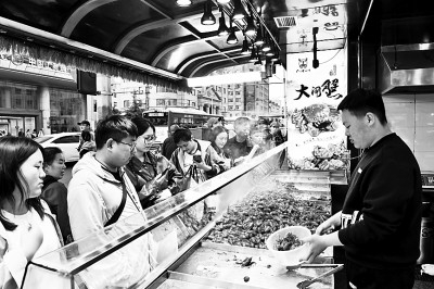     小吃摊位前排队等候美食的消费者。崔冬妮摄/光明图片