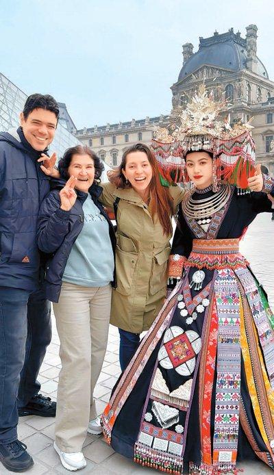 小明（右一）在法国巴黎卢浮宫前与当地民众合影。受访者供图