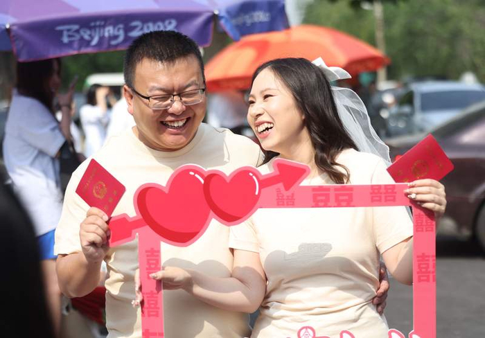 一对新人拿着结婚证开心地拍照。新京报记者 王贵彬 摄