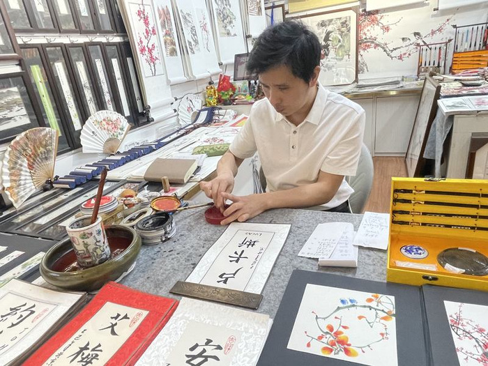 张春望在宣纸上用毛笔书写外国游客的中文名。新京报记者 吴婷婷 摄