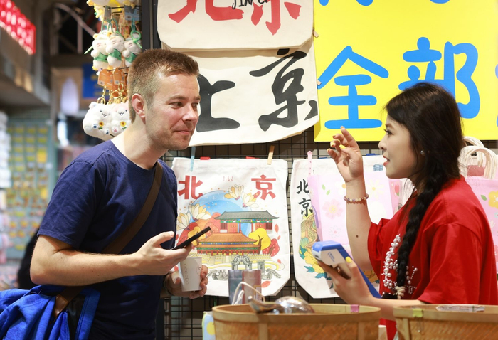 5月16日，南锣鼓巷，店员正在跟外国游客沟通便捷的支付方式。