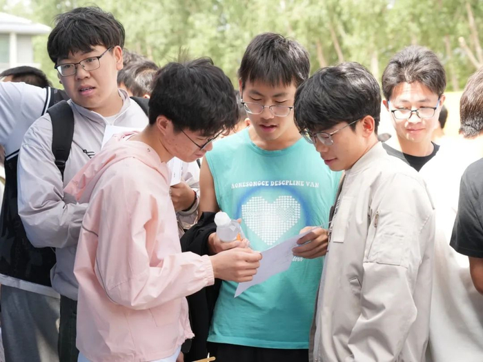 展位前，应聘者们仔细查看招聘信息。