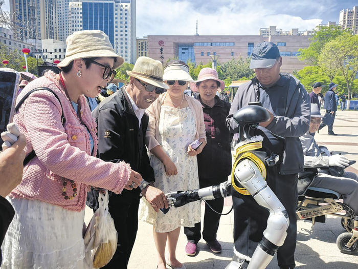 观众与宇树科技人形机器人握手互动。王菲菲 摄