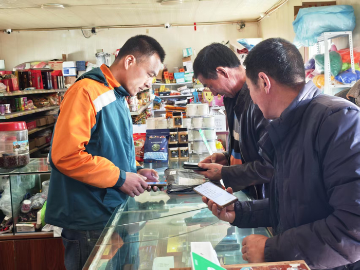 门源县桥滩村快递驿站投递员正在帮助村民取包裹（记者江晓晨  摄）