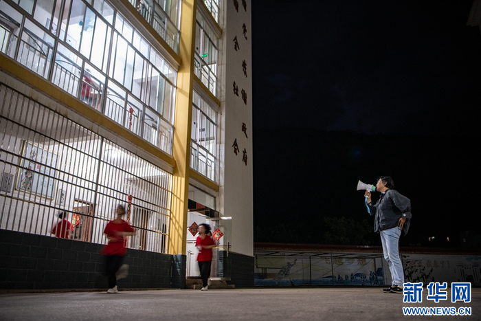张桂梅在宿舍楼前叫学生们起床（资料图）。（新华社 江文耀 摄）