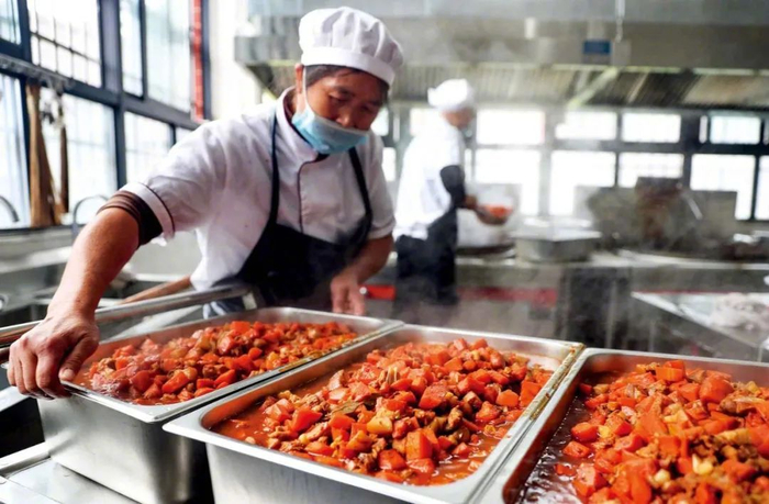 四川一所小学食堂的工作人员为学生准备“安全放心餐”。图/视觉中国