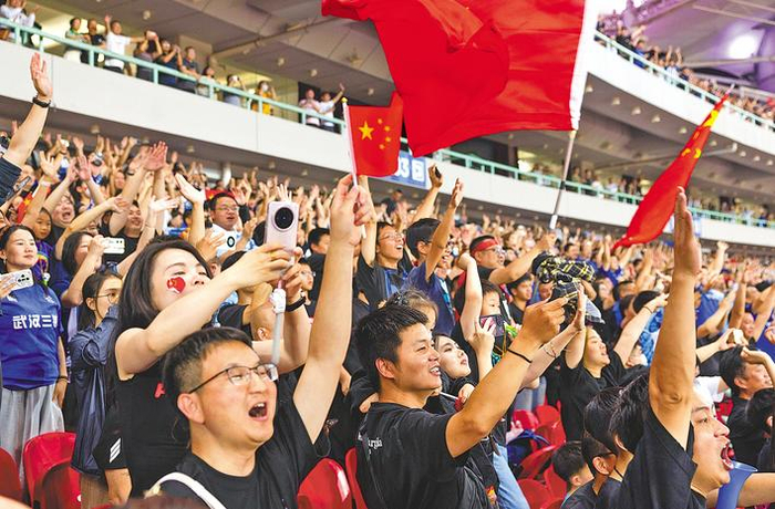 看台上球迷举起五星红旗为女足队员加油。