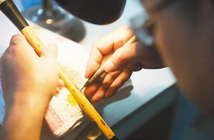 ▲ 在浙江省湖州市善琏湖笔厂，工人在传统作坊内为湖笔手工刻字。新华社记者 翁忻旸摄