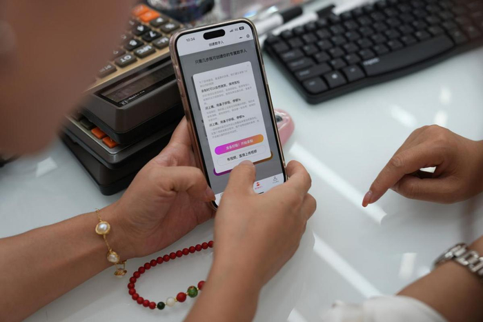 5月20日，一位义乌商户展示手机应用的AI数字人功能。（图片来源：新华社）