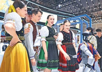 外籍参会代表在第四届中国—中东欧国家博览会暨国际消费品博览会现场与人形机器人互动。新华社记者 江汉摄