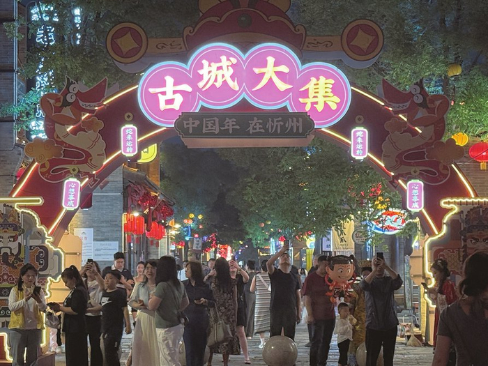 夜晚的忻州古城灯光璀璨、游人如织，特别在古城大集，游人边走边拍照留念，十分热闹。本报记者高玮摄
