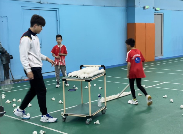 　　图为羽动羽毛球球馆内，教练带领学员回收场地上的羽毛球。