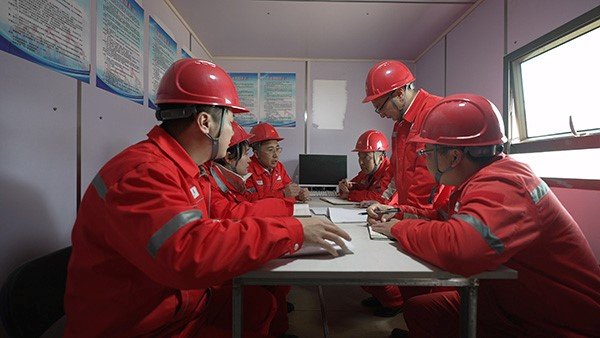 中国石油长庆油田采油十厂员工现场讨论分析技术难题 摄影：王伟杰