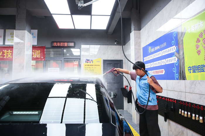 ▲ 毛仁强正在冲洗汽车车顶。摄影丨江西日报全媒体记者赵影