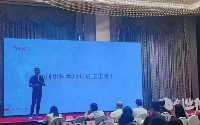 ▲某公司培训会上，大屏幕上大字写着“如何更科学地扣员工工资”，引发网友热议。图/网络视频截图