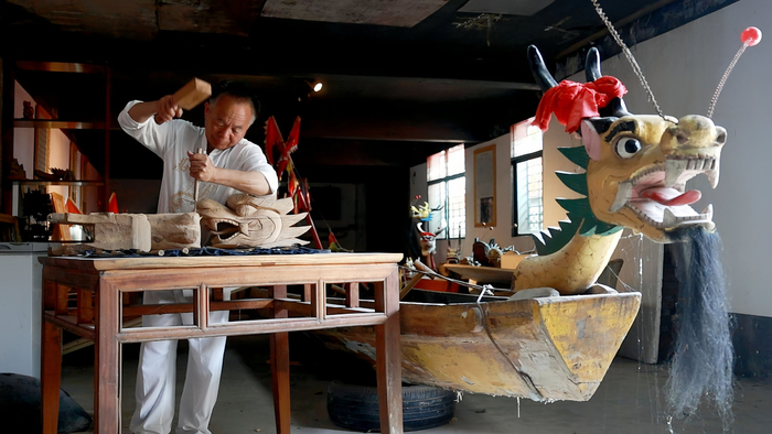 ↑许桂生在湖南省汨罗市屈子祠镇九子龙屈原龙舟厂制作龙舟。新华社发（胡清 摄）