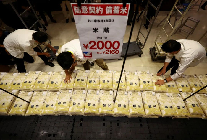 5月31日，在日本东京的一家超市，店员摆放储备米/图源：新华社
