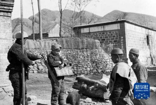 抗战时期，晋察冀边区儿童团的孩子在站岗放哨时教路过的乡民识字“加紧春耕”。沙飞 摄