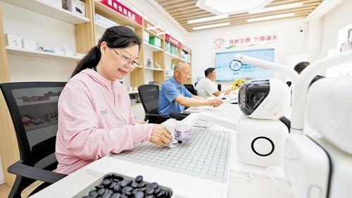 5月20日,雄安颐养·智慧养老展示馆内,南文营社区居民王秀兰(左一)正在和机器人下棋。本报记者 李 畅摄
