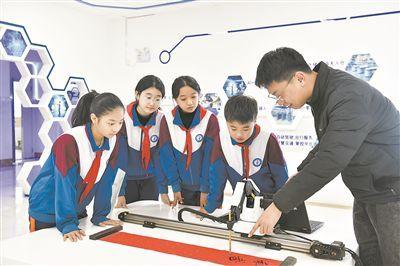 在山东日照金海岸小学,老师指导学生练习机械臂毛笔书写编程。新华社记者 郭绪雷 摄