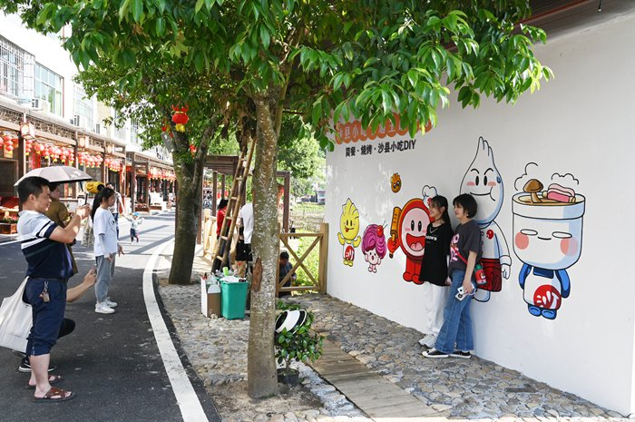 游客在俞邦村沙县小吃IP形象前打卡