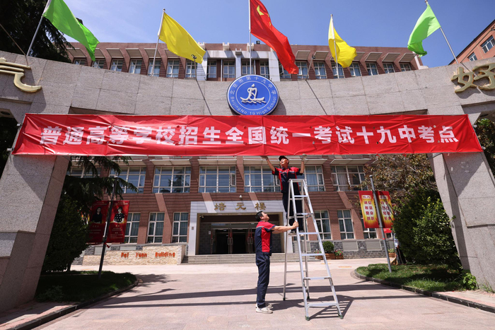 北京市第十九中学考点，工作人员正在挂横幅。新京报记者 李木易 摄