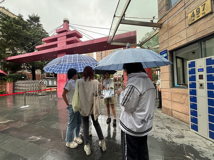 上外东校的几位同学围在考点外的校门口对起了答案。澎湃新闻记者 韩晓蓉 图