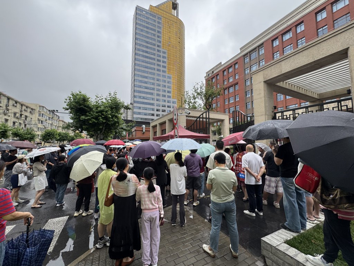 华东师范大学附属东昌中学考点门口，站满撑伞等待的考生家长。澎湃新闻记者 李菁 图